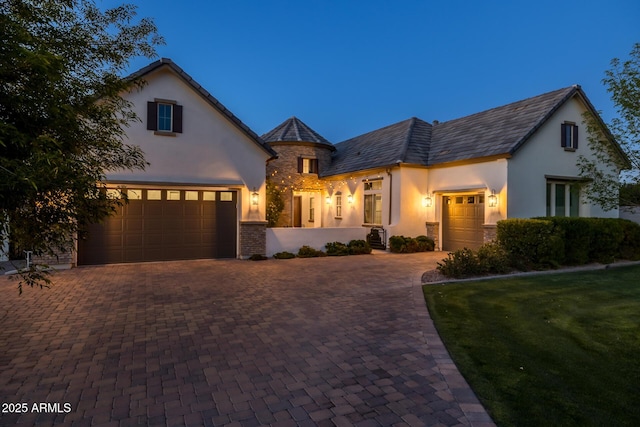 view of front facade with decorative driveway, a garage, and a front yard