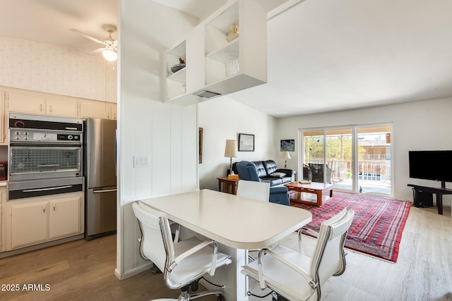 dining space featuring wallpapered walls, ceiling fan, and light wood finished floors