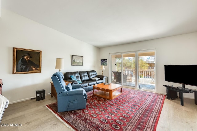 living area with lofted ceiling, light wood-style flooring, and baseboards