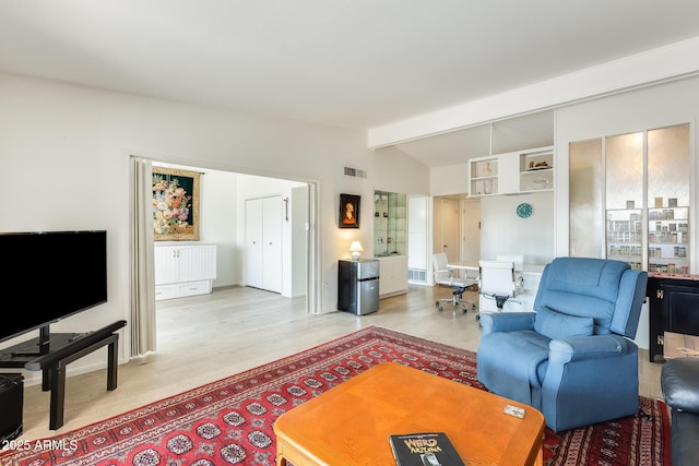 living room featuring light wood-type flooring, visible vents, and vaulted ceiling with beams