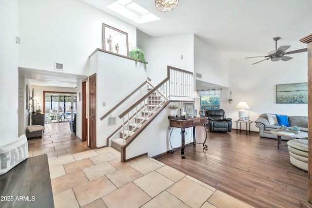 staircase featuring a skylight, a wealth of natural light, ceiling fan, and wood-type flooring