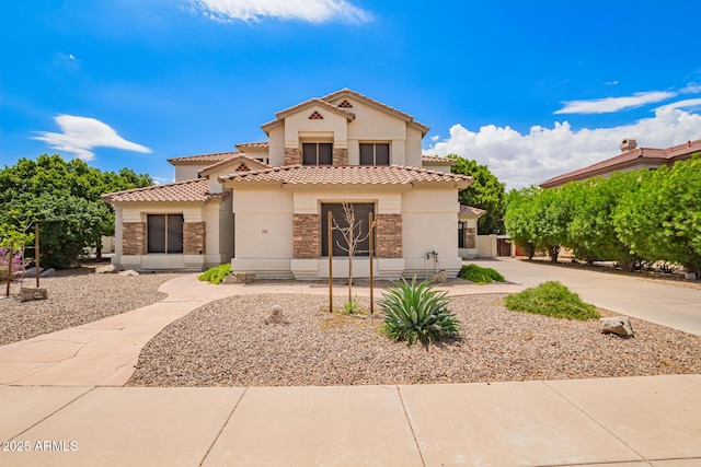 mediterranean / spanish home with stone siding, stucco siding, and a tile roof