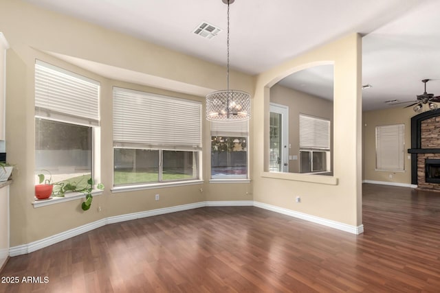 unfurnished dining area with a ceiling fan, wood finished floors, a chandelier, and a fireplace