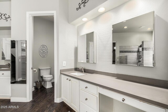 bathroom with wood finished floors, vanity, baseboards, toilet, and recessed lighting