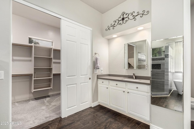 full bathroom featuring vanity, wood finished floors, a soaking tub, and baseboards