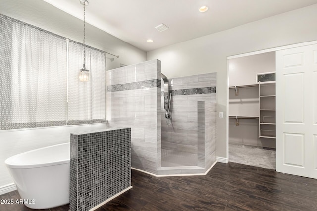 bathroom featuring walk in shower, a soaking tub, wood finished floors, recessed lighting, and a walk in closet