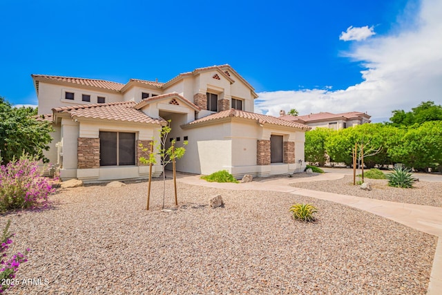 mediterranean / spanish home featuring stucco siding, stone siding, and a tiled roof