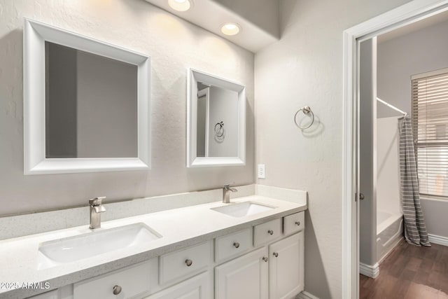 bathroom featuring washtub / shower combination, wood finished floors, and double vanity