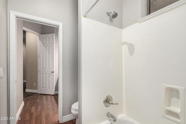 full bath with wood finished floors, bathing tub / shower combination, and toilet