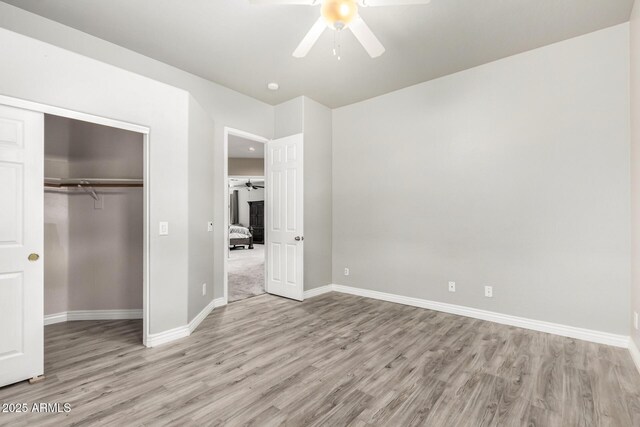 unfurnished bedroom with light wood-type flooring, baseboards, a closet, and ceiling fan
