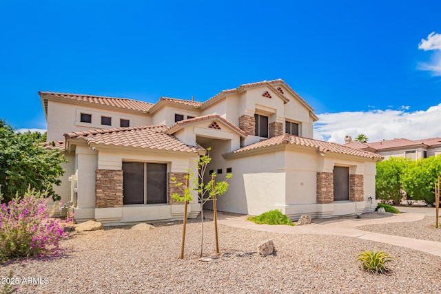 mediterranean / spanish-style home featuring stone siding, stucco siding, and a tile roof