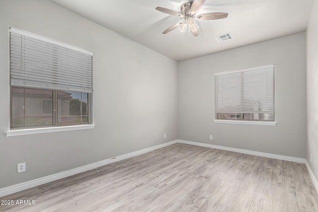 spare room with wood finished floors, a ceiling fan, and baseboards