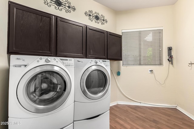 laundry room featuring cabinet space, washer and dryer, baseboards, and wood finished floors