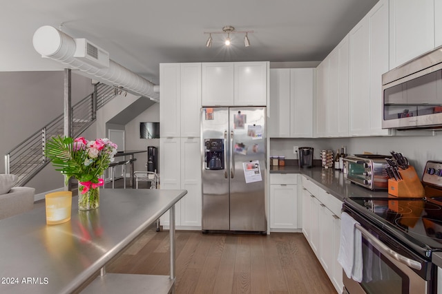 kitchen featuring appliances with stainless steel finishes, hardwood / wood-style floors, and white cabinets