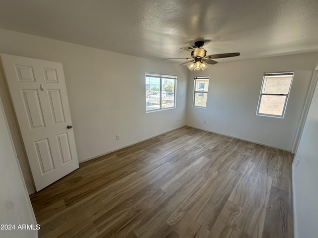 spare room with ceiling fan, a textured ceiling, and light hardwood / wood-style floors