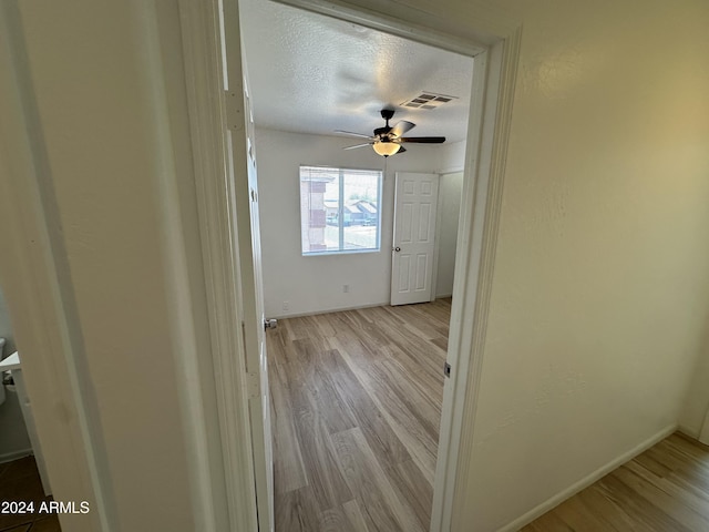 corridor featuring a textured ceiling and light wood-type flooring