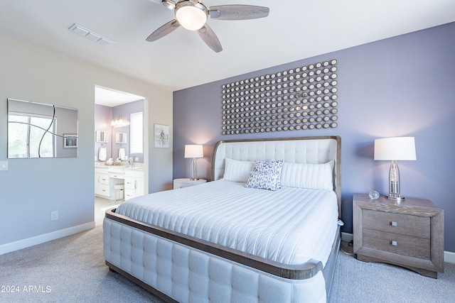 bedroom featuring ceiling fan, light colored carpet, and ensuite bath