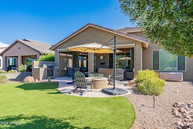 back of property with a patio, an outdoor kitchen, a fire pit, and a yard