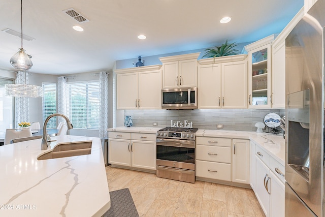 kitchen featuring hanging light fixtures, sink, tasteful backsplash, stainless steel appliances, and light stone countertops