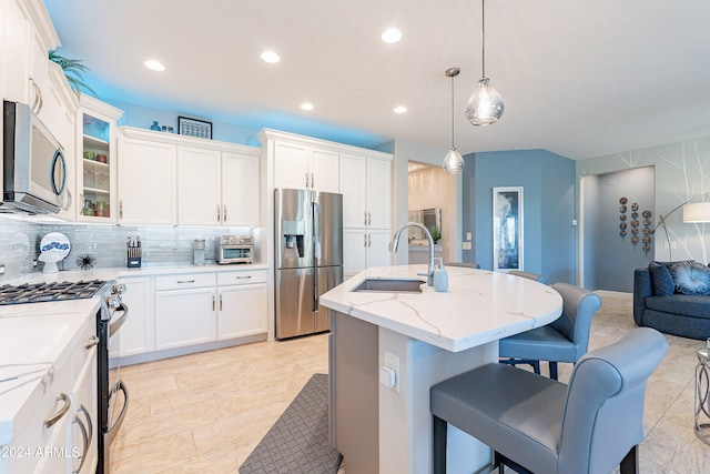 kitchen featuring sink, an island with sink, decorative backsplash, stainless steel appliances, and decorative light fixtures