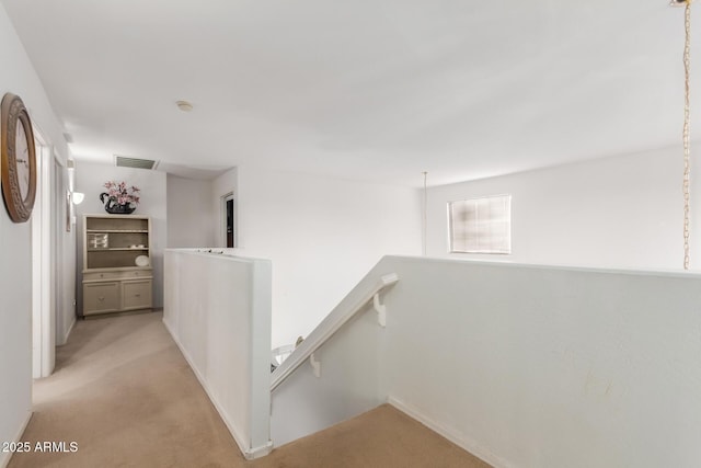 hallway featuring visible vents, light carpet, and an upstairs landing