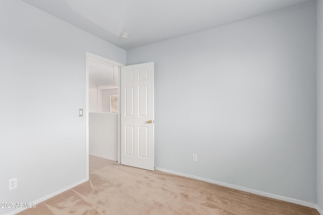 unfurnished room with baseboards and light colored carpet