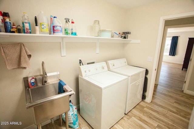 laundry room with separate washer and dryer, sink, and light hardwood / wood-style flooring