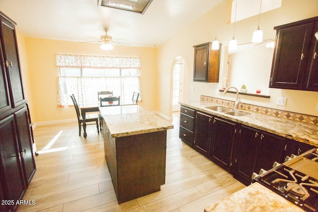 kitchen with decorative light fixtures, a center island, sink, and light wood-type flooring