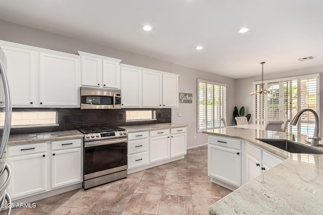 kitchen featuring appliances with stainless steel finishes, sink, pendant lighting, and white cabinets