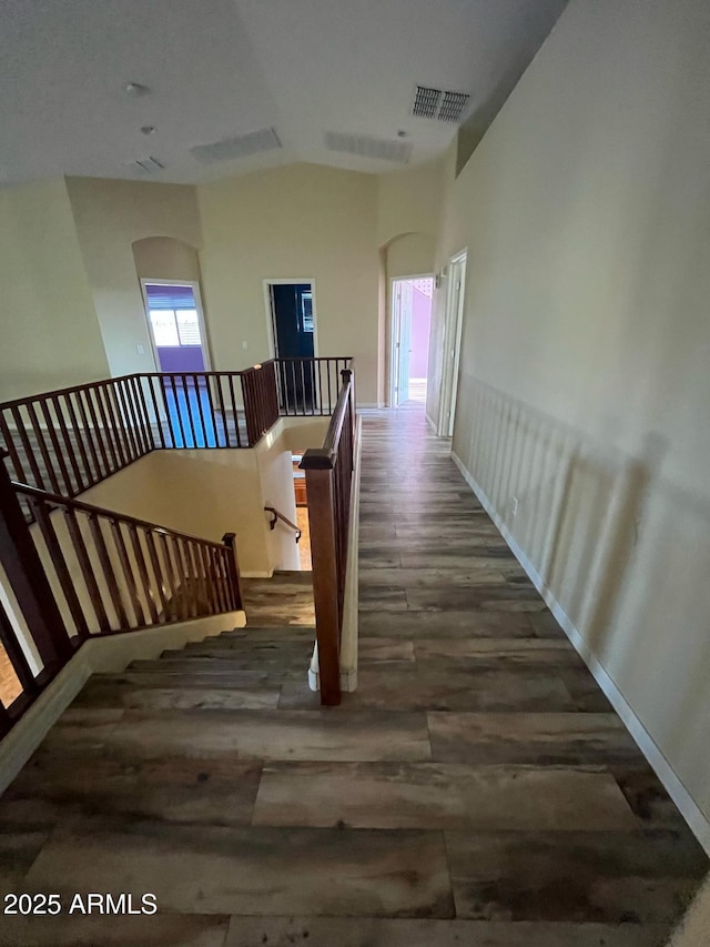 corridor with baseboards, an upstairs landing, wood finished floors, and visible vents