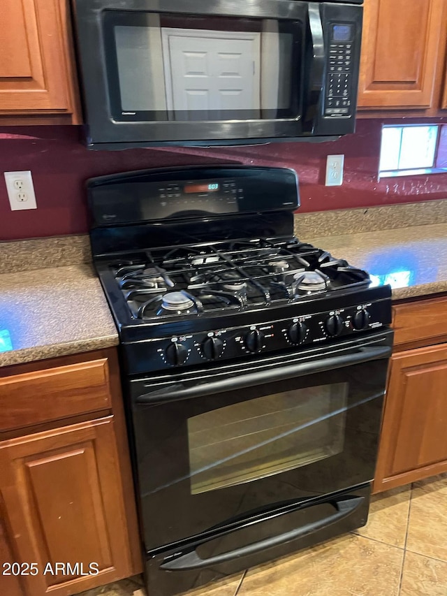 kitchen with brown cabinetry, light countertops, light tile patterned flooring, and black appliances