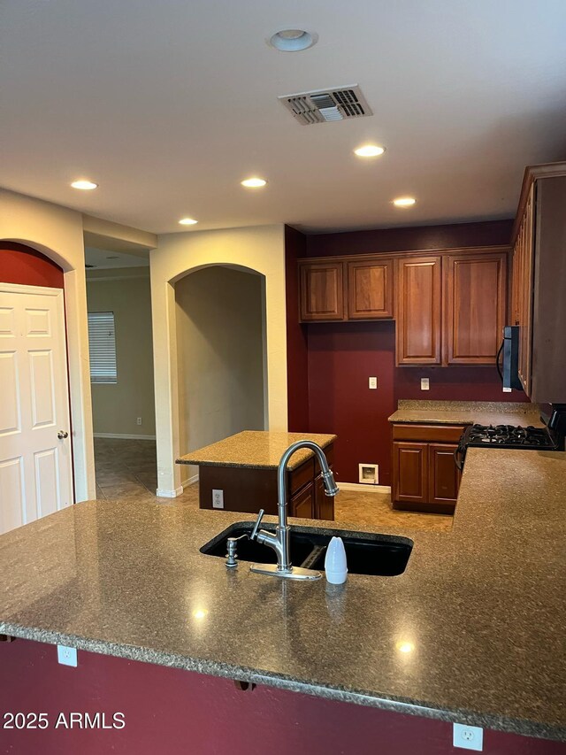 kitchen featuring a sink, arched walkways, recessed lighting, and visible vents