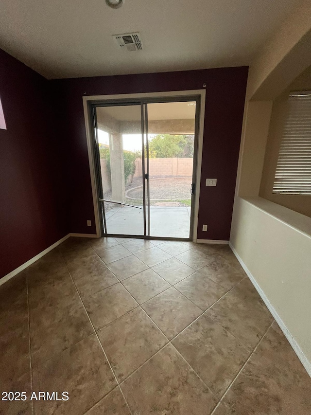 tiled spare room featuring baseboards and visible vents