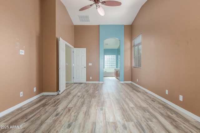 spare room with ceiling fan, visible vents, arched walkways, light wood-type flooring, and baseboards