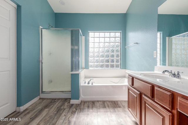 bathroom featuring vanity, a bath, a shower stall, and wood finished floors