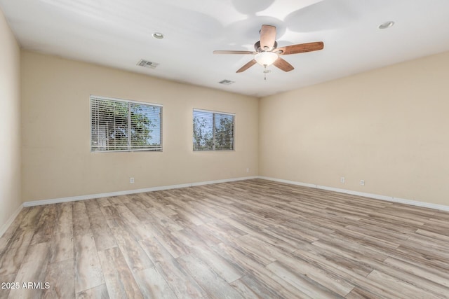 spare room featuring baseboards, ceiling fan, visible vents, and light wood-style flooring