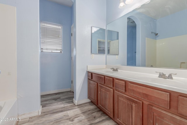 bathroom with double vanity, a sink, wood finished floors, and a washtub