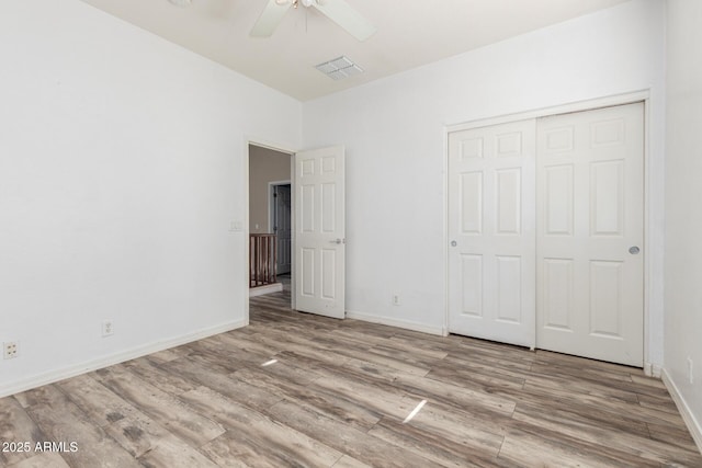 unfurnished bedroom featuring baseboards, a closet, wood finished floors, and visible vents