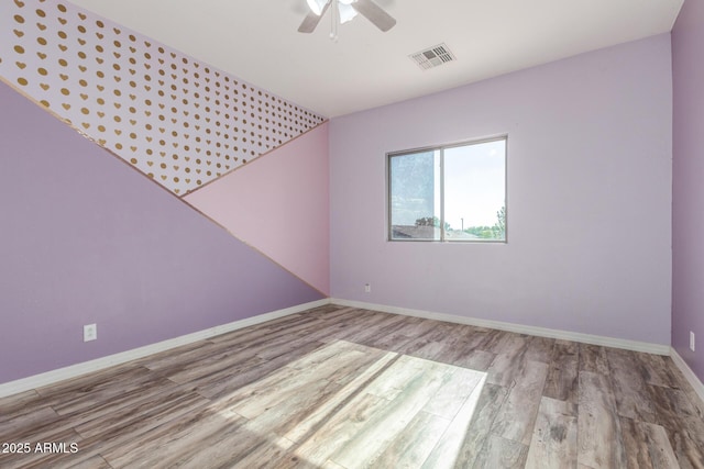 unfurnished room featuring baseboards, a ceiling fan, wood finished floors, and visible vents