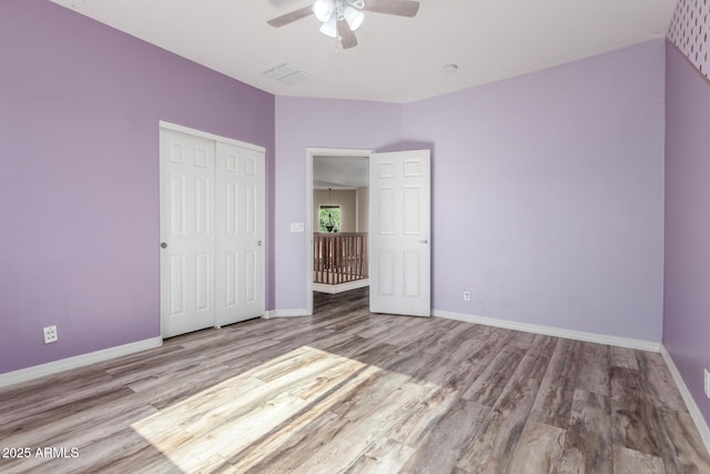 unfurnished bedroom featuring baseboards, wood finished floors, and a closet