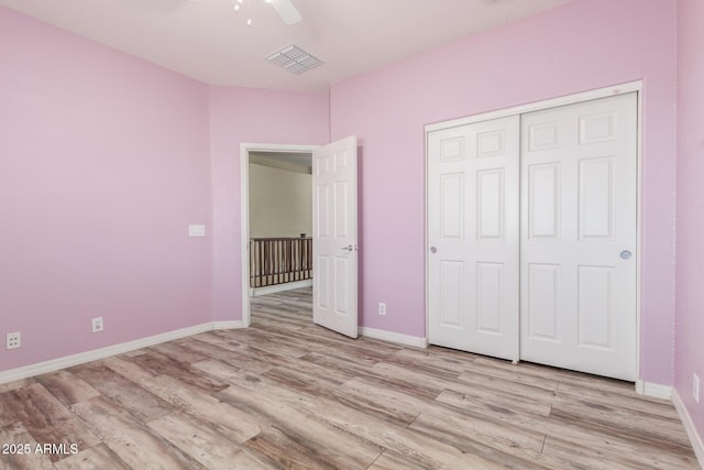 unfurnished bedroom with baseboards, a closet, light wood-type flooring, and visible vents