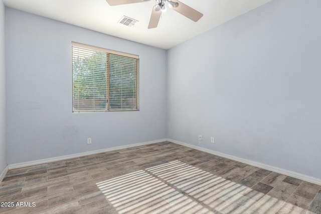 spare room with baseboards, ceiling fan, wood finished floors, and visible vents