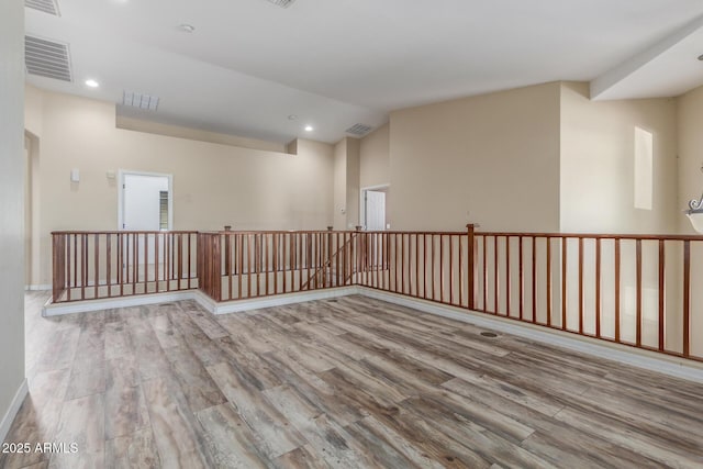 empty room with vaulted ceiling, wood finished floors, and visible vents