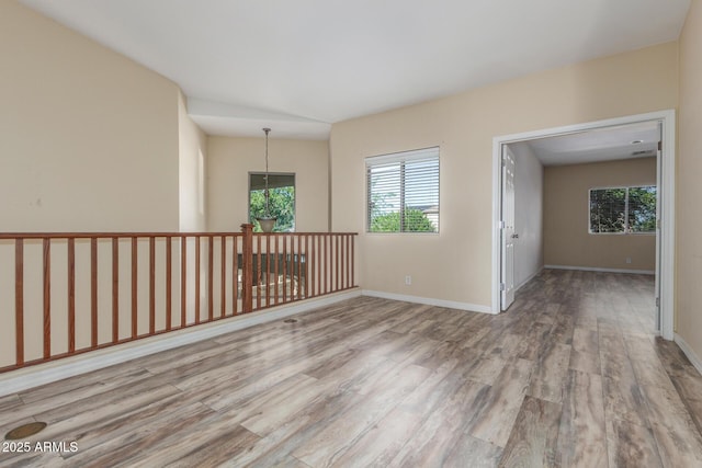 unfurnished room with baseboards, wood finished floors, and a wealth of natural light