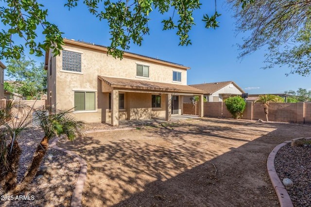 back of house with a fenced backyard, a patio, and stucco siding