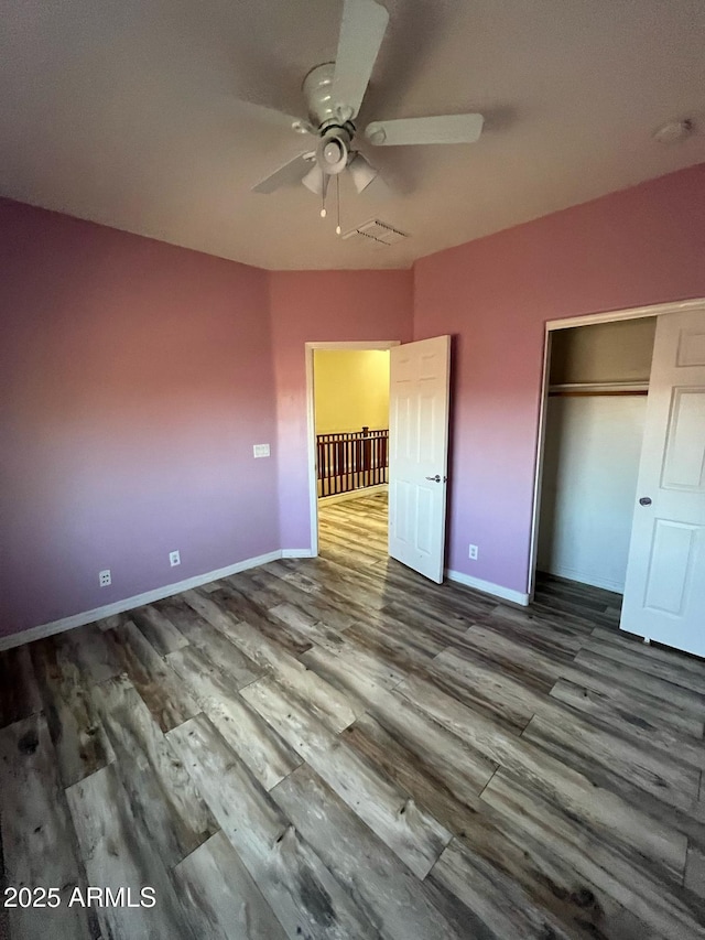 unfurnished bedroom with baseboards, a closet, wood finished floors, and visible vents