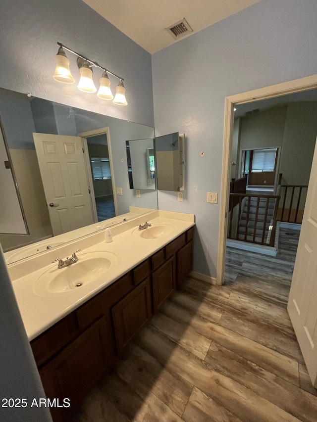 bathroom featuring double vanity, visible vents, a sink, and wood finished floors