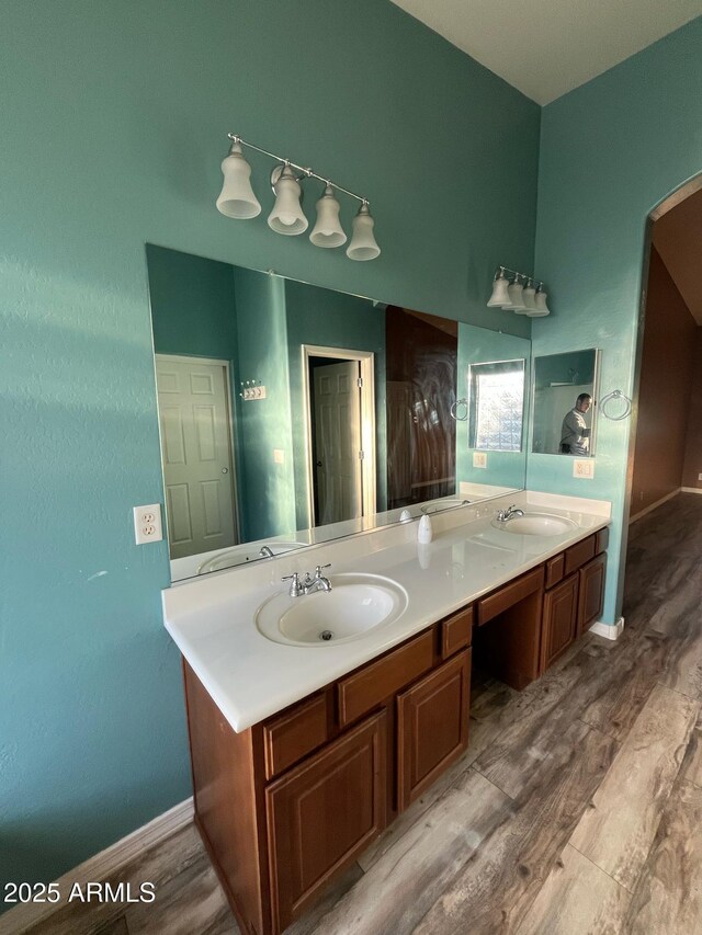 full bathroom featuring double vanity, a sink, and wood finished floors