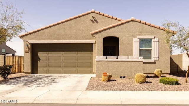 mediterranean / spanish house featuring concrete driveway, fence, an attached garage, and stucco siding