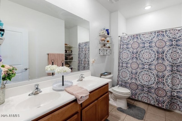 bathroom with double vanity, a sink, toilet, and tile patterned floors